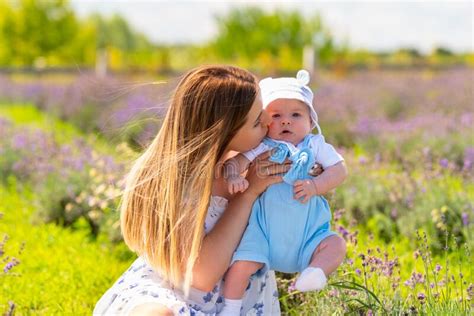 Loving Mother Kissing Her Baby Son Outdoors In Summer Stock Photo