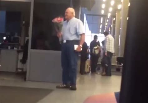 older gentleman greets wife at airport with flowers