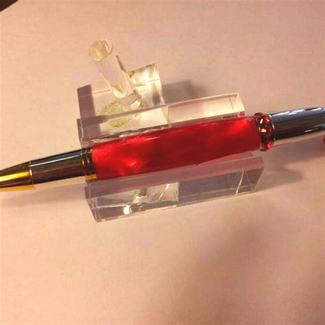 A Red Fountain Pen Sitting On Top Of A Table Next To A Small Glass