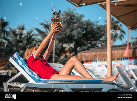 Happy Female With Pineapple Cocktail Lying On The Sun Lounger Under A