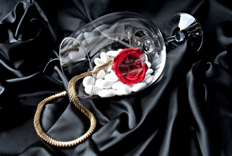 Бокал с золотой цепочкой красной розой и белыми камнями на черном
