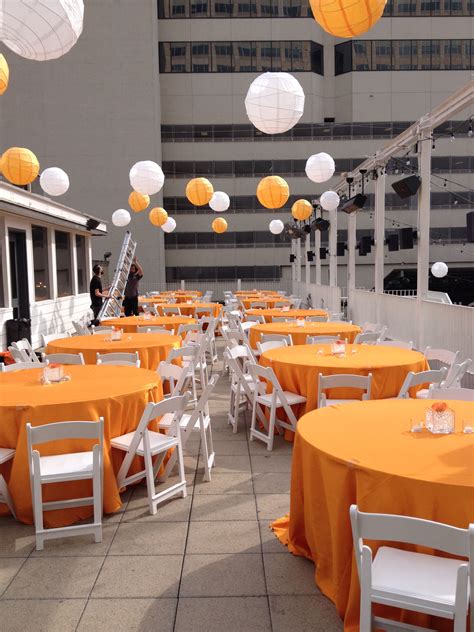 Tables And Chairs Are Set Up Outside With Orange Tablecloths On Them