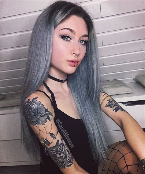 a woman with long grey hair and tattoos on her arms is posing for the camera