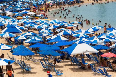 crowd of people on porto da barra beach having fun under strong summer sun editorial image