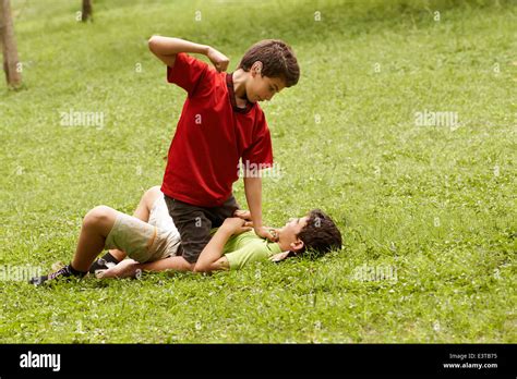 Two Young Brothers Fighting And Hitting On Grass In Park With Older