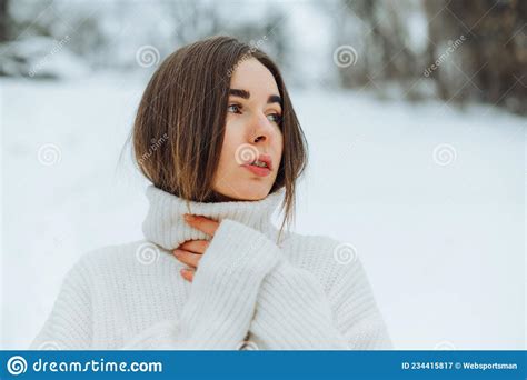 Portrait Of A Beautiful Woman In A White Sweater On A Snowy Street