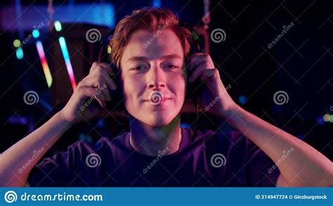 A Cute Young Gamer Guy Puts A Headset On His Head In The Computer Room