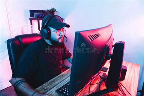 Hispanic Professional Gamer Wearing Headphones Immersed In Playing An