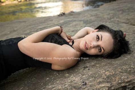 A Beautiful Woman Laying On Top Of A Rock Next To A River