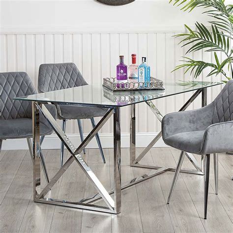 A Glass Dining Table With Grey Chairs And Bottles On The Top In Front Of A White Wall
