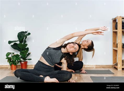 Immersed Women Practicing Yoga Doing Sitting Side Bend On A Mat In