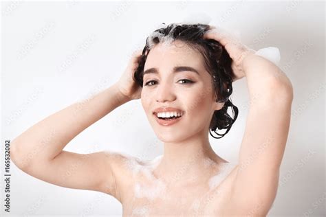Young Woman Washing Hair While Taking Shower On White Background Stock