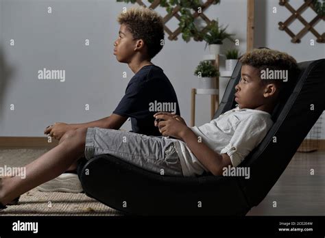 Two Mixed Race Brothers Play To Play Station Seated Together Indoor
