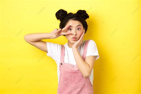 cute asian girl posing with vsign and pout on yellow backdrop photo background and picture for