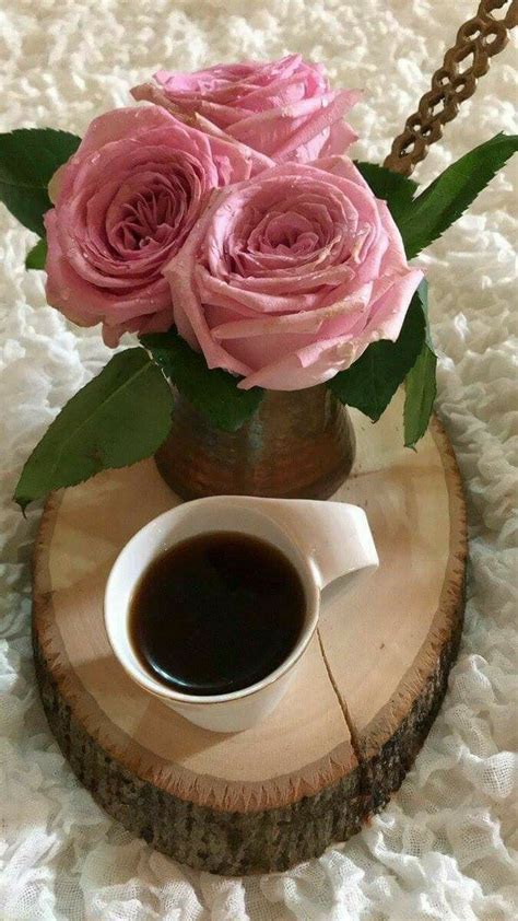 A Cup Of Coffee And Some Pink Roses In A Vase On A Wood Slice With Lace