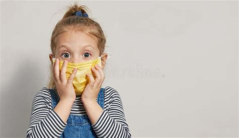 Sick And Surprised Little Girl Child In A Protective Medical Mask Holds
