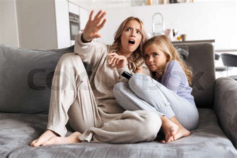 scared girls sisters on sofa at home indoors watch tv horror film together stock image