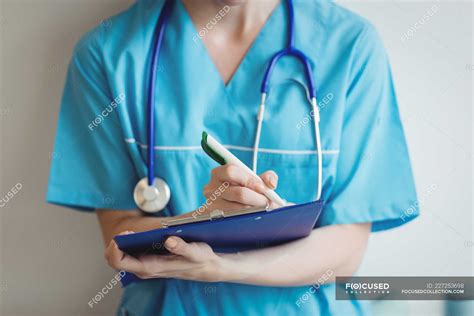 Mid Section Of Nurse Writing On Clipboard At Hospital — Job Medical