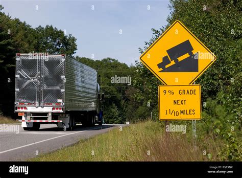 Semi Truck Drives Past A Road Sign Warning Drivers Of Steep Hill 9