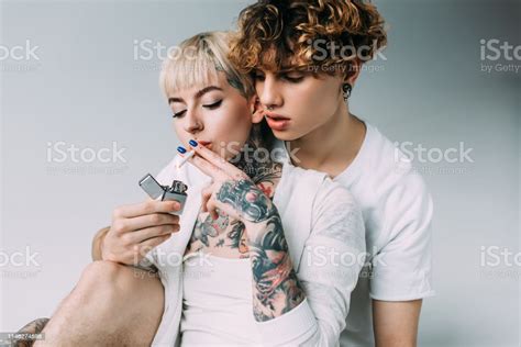 Blonde Tattooed Girl Smoking Cigarette Near Handsome Man With Lighter
