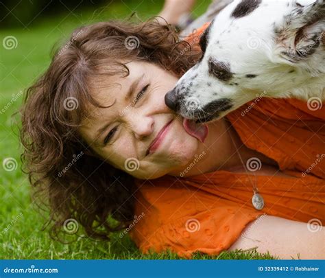 Vrouw Die Weerzinwekkend Gezicht Maken Terwijl Wordt Gelikt Door Haar Hond Stock Foto