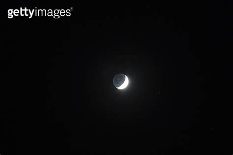 Moon Waxing Crescent And Grey Light Against Dark Starry Sky