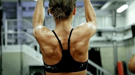 The Back Of A Woman In A Black Sports Bra Top Doing Exercises On A Gym