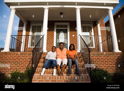 African Mother Daughter And Son Sitting On Front Stoop Of House Stock