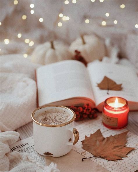 A Cup Of Coffee Sitting On Top Of A Table Next To An Open Book And Candle