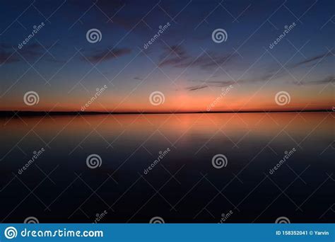 The Sun Setting Over Water With Clouds And Blue Sky In The Background