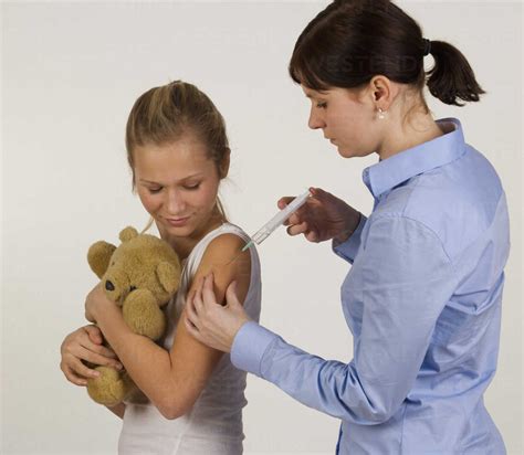 Female Doctor Giving Injection To Teenage Girl Stock Photo