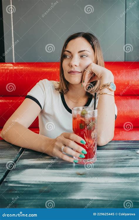 Woman Sitting In Cafe And Drinking Red Cocktail Pretty Lady With Strawberry Mojito Drink In Bar
