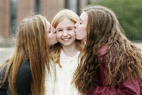 Close Up Of Smiling Sisters Kissing Outdoors Stock Photo Dissolve