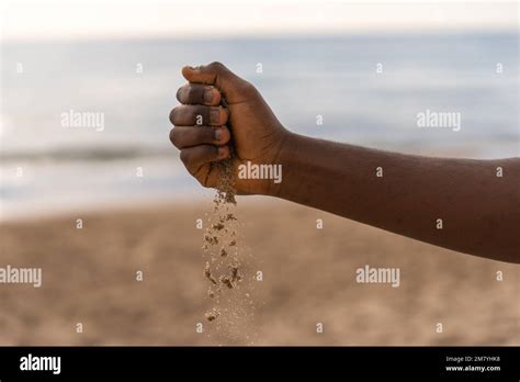 Crop Anonymous African American Male Pouring Sand From Hand During Day