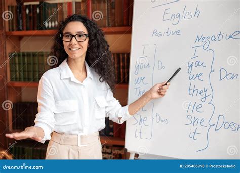 Smiling Female Teacher Writing At Whiteboard Explaining Rules Stock