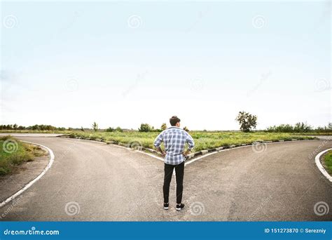 Young Man Standing At Crossroads Concept Of Choice Stock Photo Image