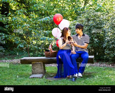 Horizontal Photo Of Young Adult Couple Sitting On Log Bench With