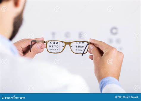 Optician Holds Glasses In Front Of Eyesight Test Chart Stock Photo