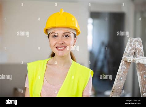 Portrait Of Positive Builder Woman In Yellow Vest And Safety Helmet