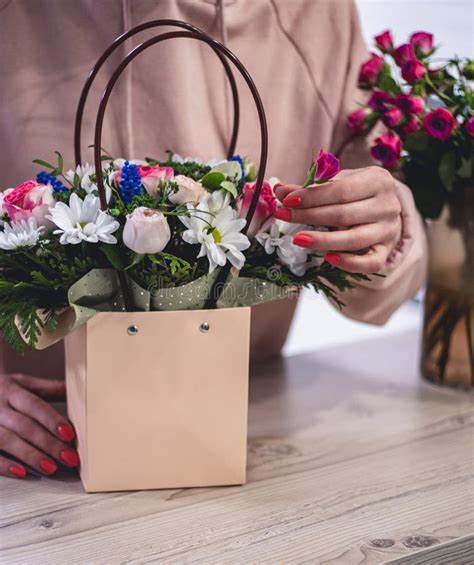 Female Picking Up Bouquet Of Different Flowers In Paper T Bag With