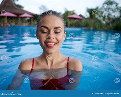 Woman Stands In The Pool With Closed Eyes And Shows Tongue In Landscape