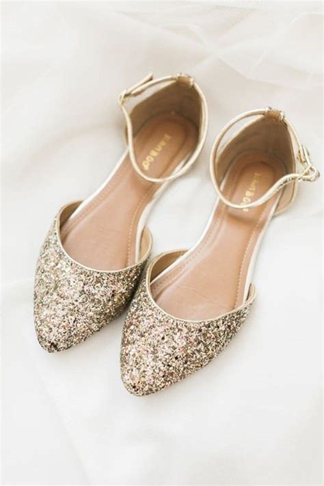 A Pair Of Gold Glitter Shoes Sitting On Top Of A White Sheet