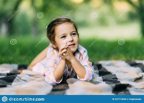 Young Child Girl Laying Down On Green Grass Lawn On Warm Summer Day