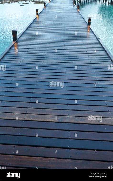 Raised Walkway Leading To Over Water Villas At Night In The Maldives