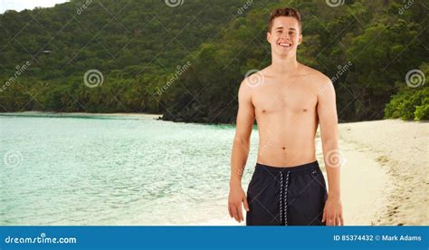 Il Ritratto Del Tipo Attraente Che Sta Senza Camicia Nella Nuotata Mette Sulla Spiaggia