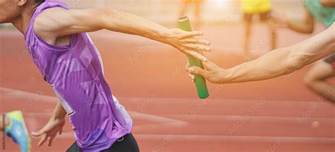 Professional Athlete Passing A Baton To The Partner Against Race On