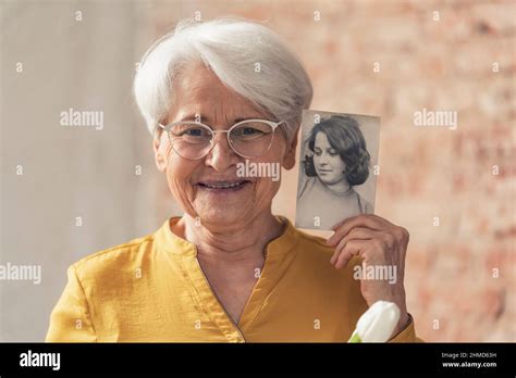 Grinning And Content Grey Haired Grandma Comparing Herself To Her Old