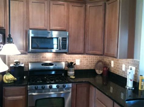 Subway tile is a classic choice for a kitchen backsplash. Toffee cabinets, black granite, sandy brick tile ...
