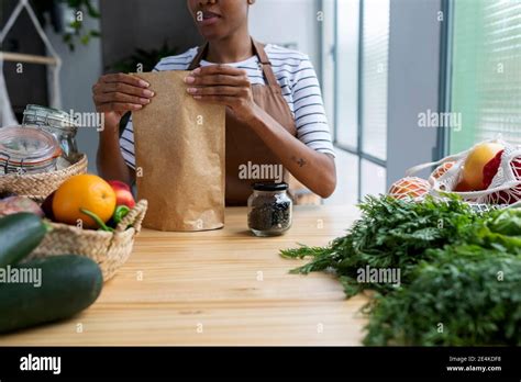 Woman With Apron In Kitchen Unpacking Freshly Bought Organic Fruit