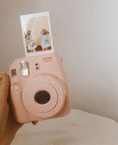 A Person Holding Up A Pink Camera With An Instax Photo On The Front